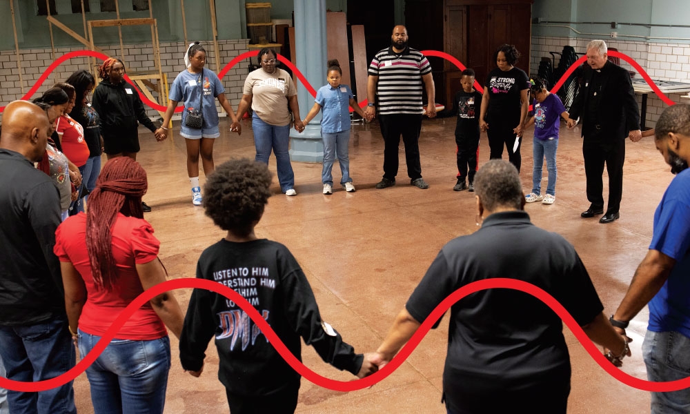 Father Mitch Doyen, far right, prayed with St. Louis Catholic Academy students and their families at a retreat June 7 at Most Holy Trinity Church, part of St. Josephine Bakhita Parish in St. Louis. Eighteen students and family members received the sacraments of initiation the next day